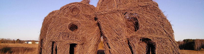 "Lean on Me," a Stickworks art installation by Patrick Dougherty - woven stick chapel-like structures leaning against each other.