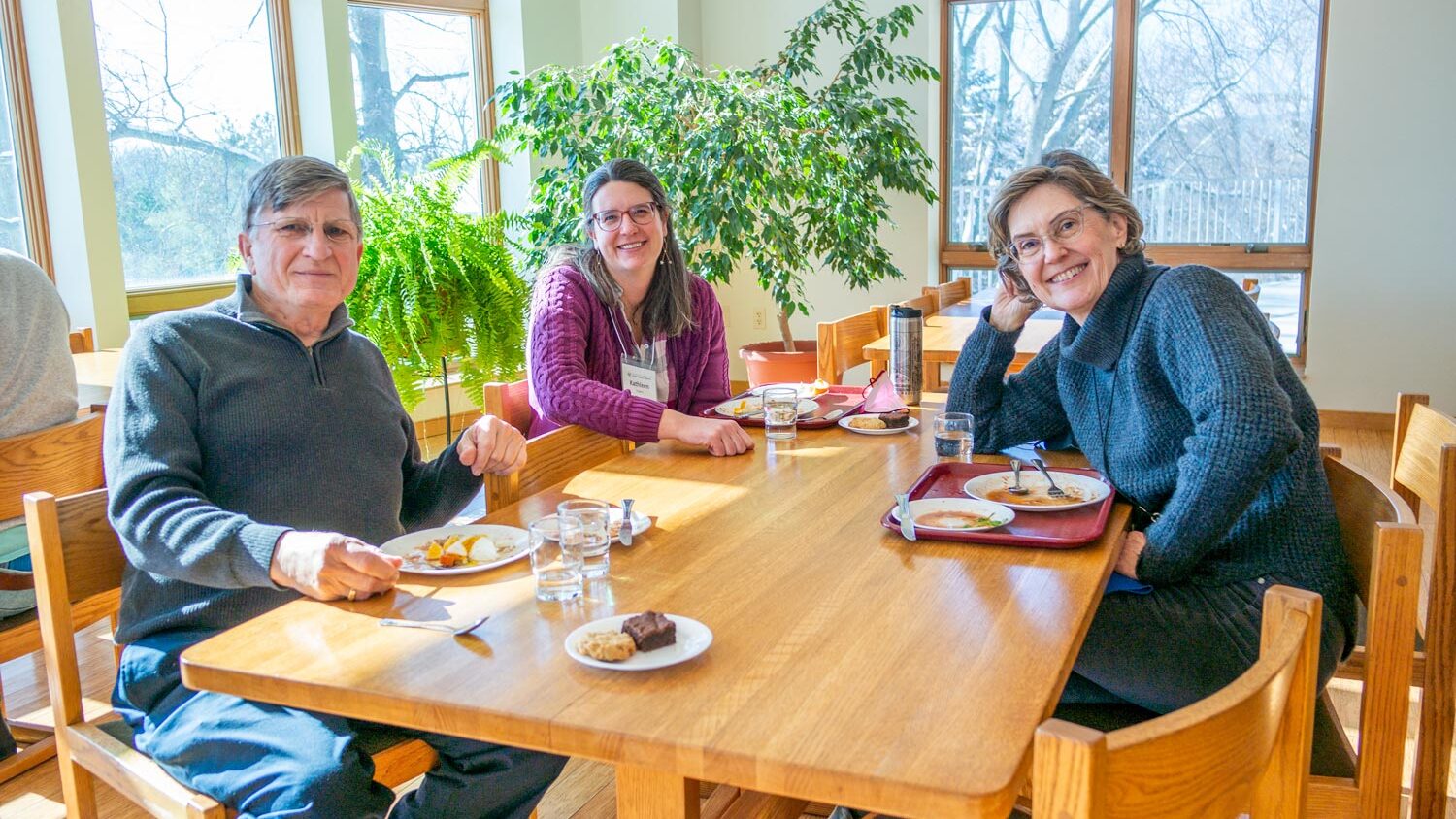 Three people looking at the camera and having a meal at the monastery